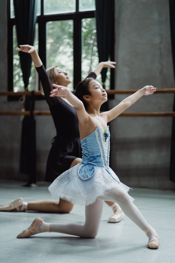 Full body side view of ethnic ballerina teaching dance moves with personal trainer in ballet class
